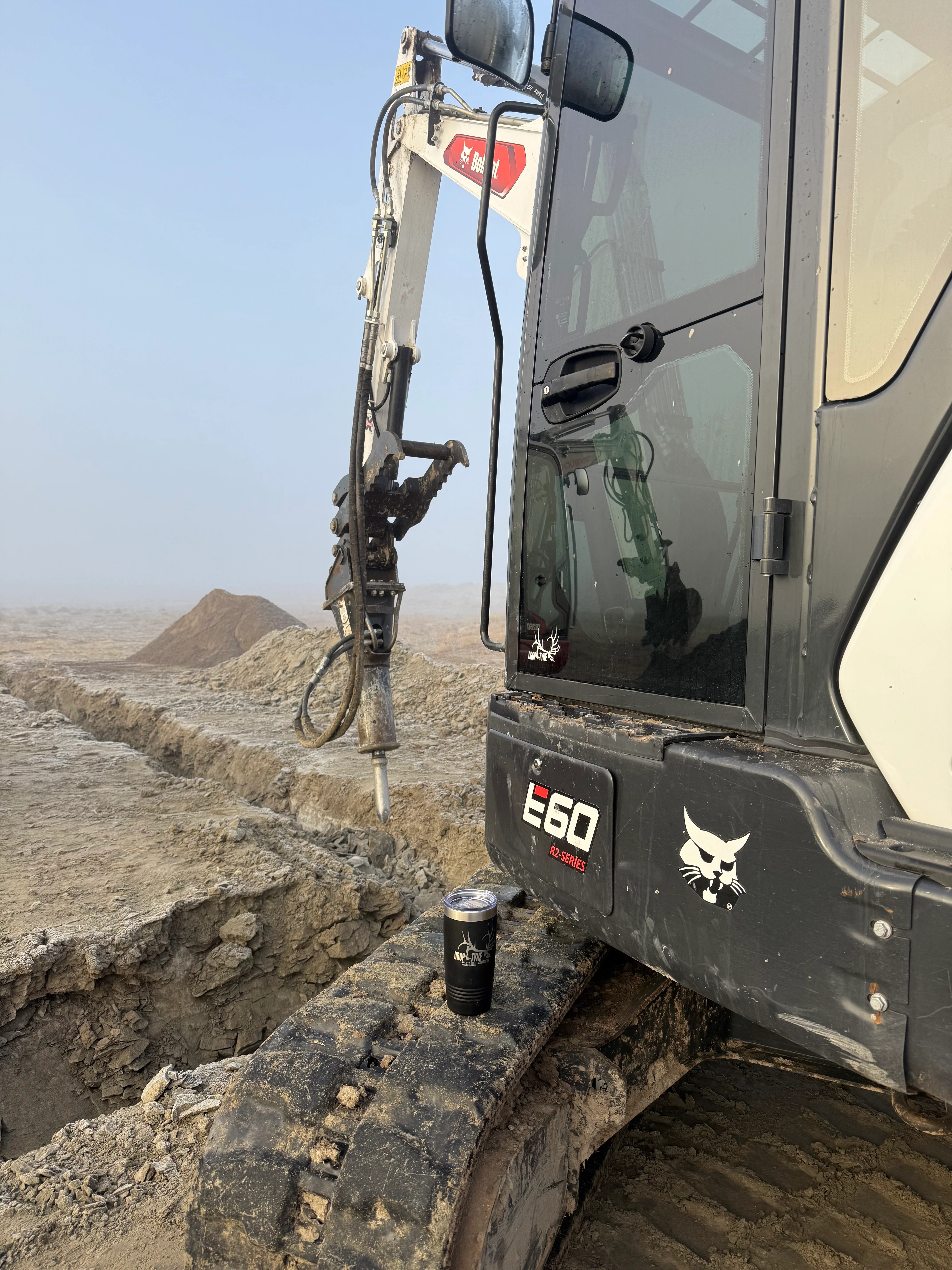 Compact excavator with hydraulic breaker attachment mounted on truck, demolishing concrete and stone