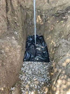 Drainage pipe installed in trench with gravel base and soil walls