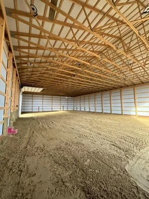 Interior arena with timber roof framing and compacted dirt floor grading