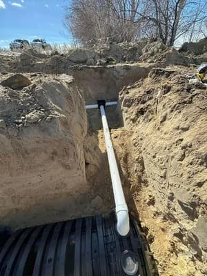 Excavated drainage trench with PVC pipe installation in earthen channel