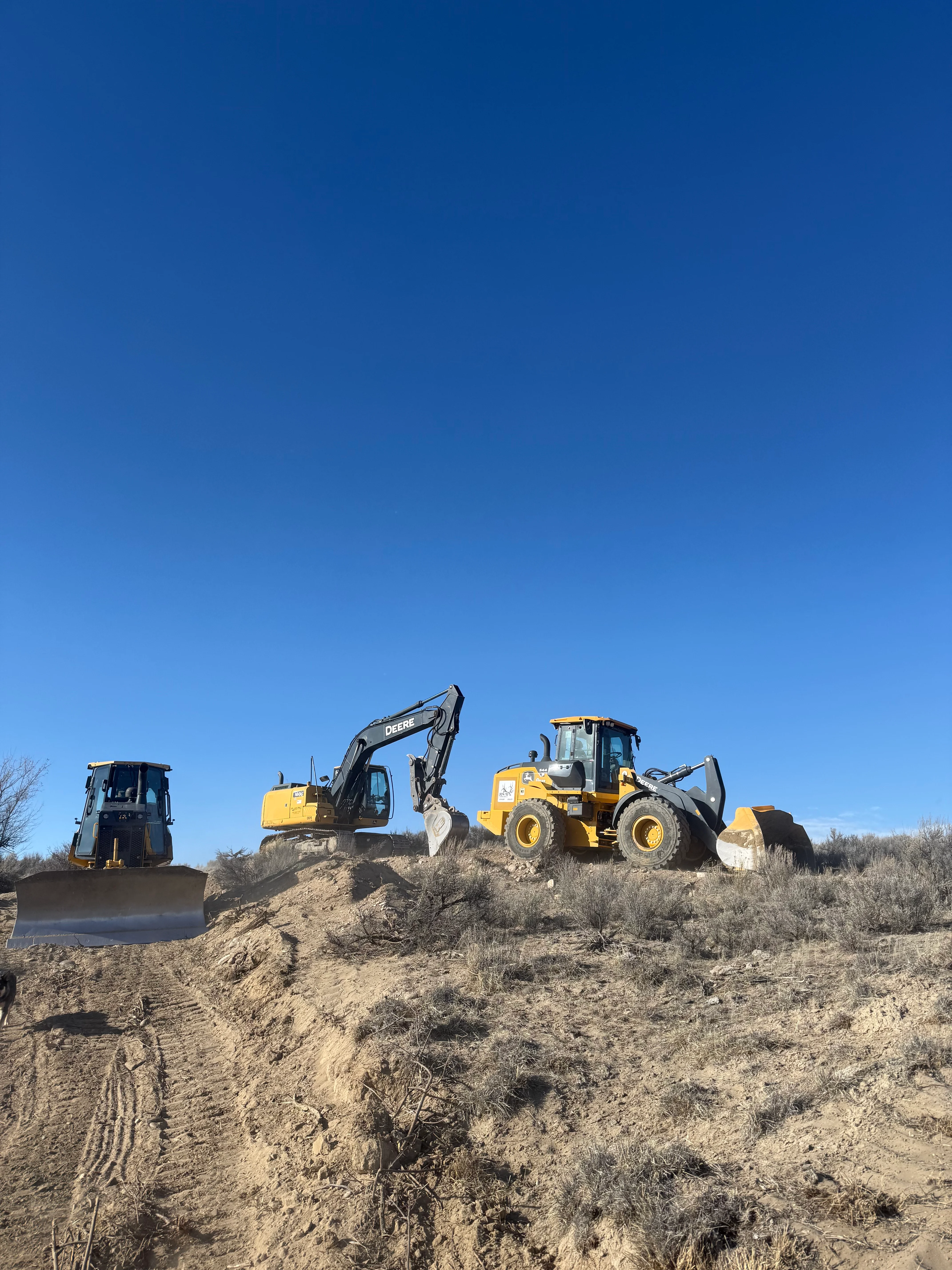 Excavator and wheel loader performing soil grading and site preparation with heavy equipment