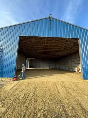 Metal frame agricultural building with blue corrugated siding and gravel base preparation